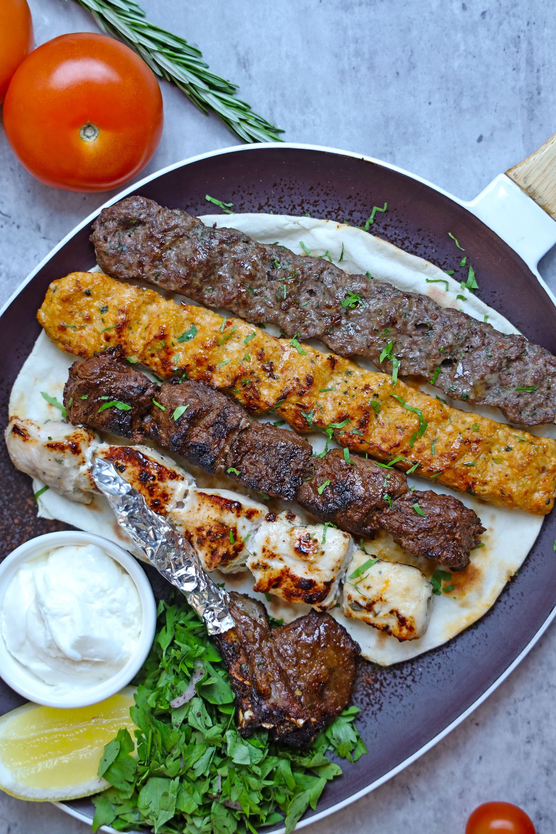 Delicious grilled meat kebabs served with pita bread, fresh herbs, and yogurt sauce.