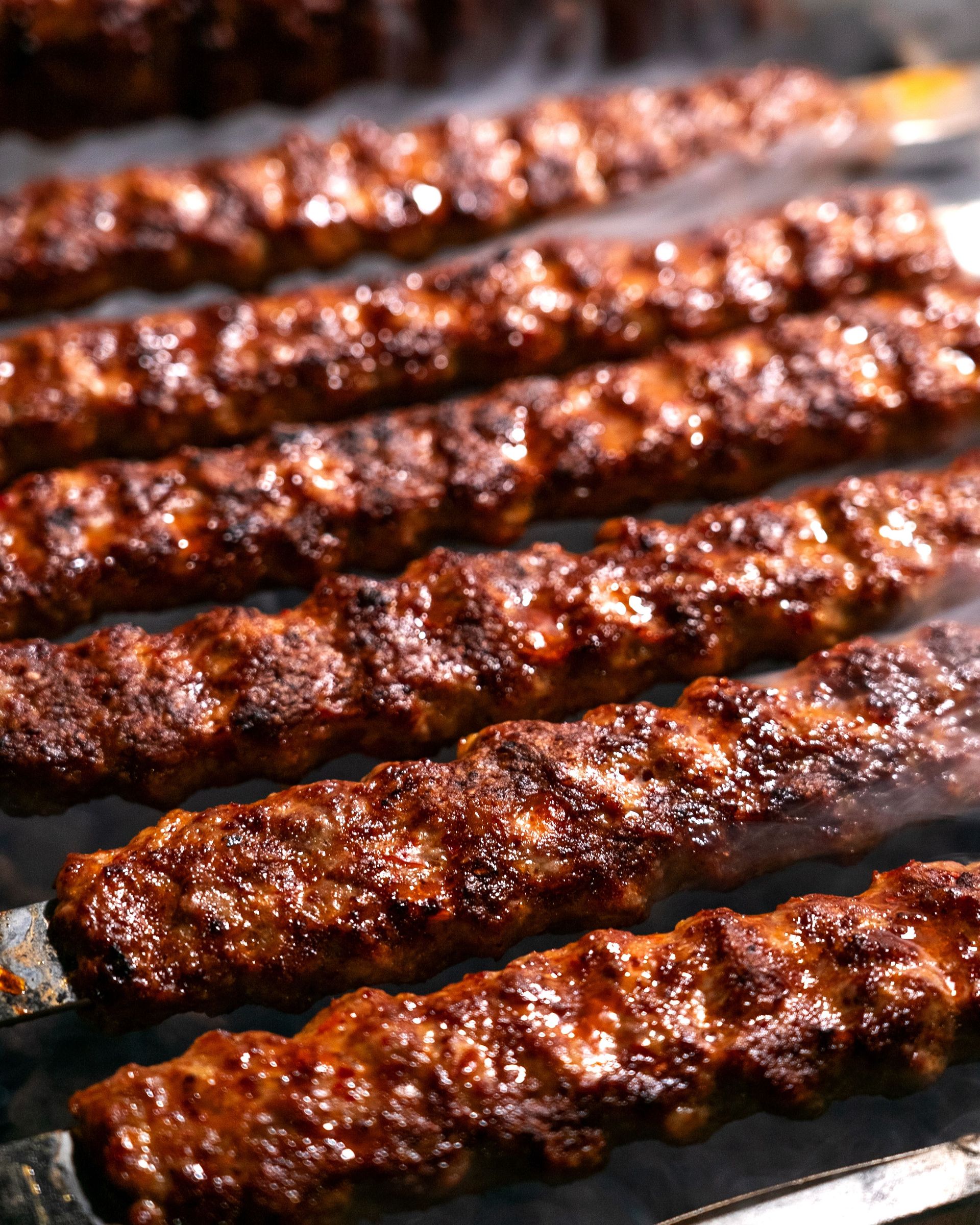 Close-up of sizzling grilled seekh kebabs on skewers, rich in spices and char-grilled flavors.