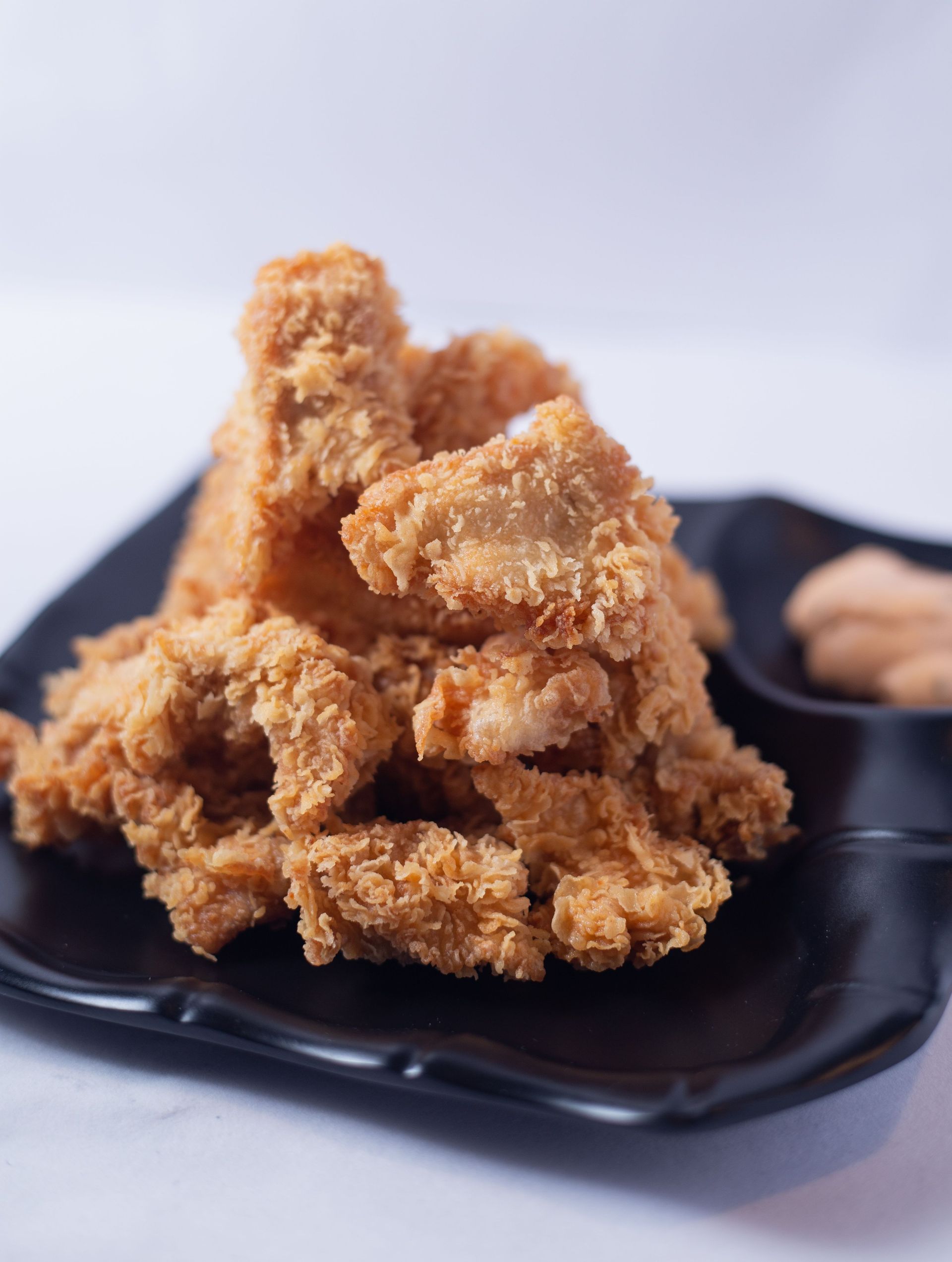 Delicious crispy fried chicken pieces served on a stylish black plate.