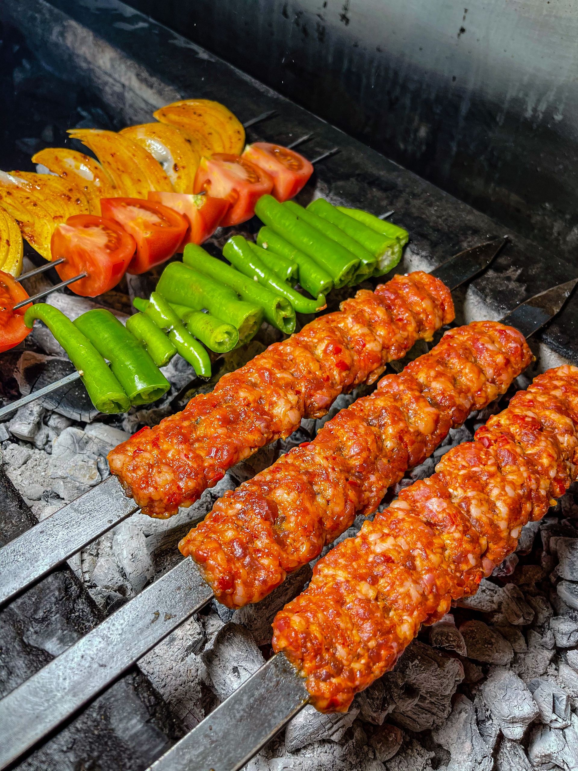 Close-up of delicious kebabs and colorful vegetables roasting on a charcoal grill. Perfect for summer BBQ ideas.